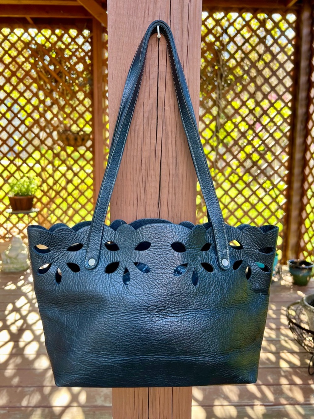 Black leather tote bag featuring a scalloped top edge